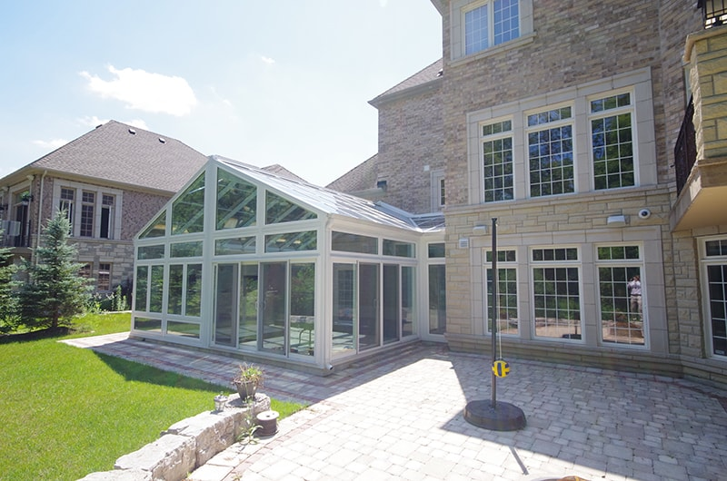 Exterior of a Four Seasons Cathedral Room Attached to a Home Next to a Stone Patio with a Tetherball on It